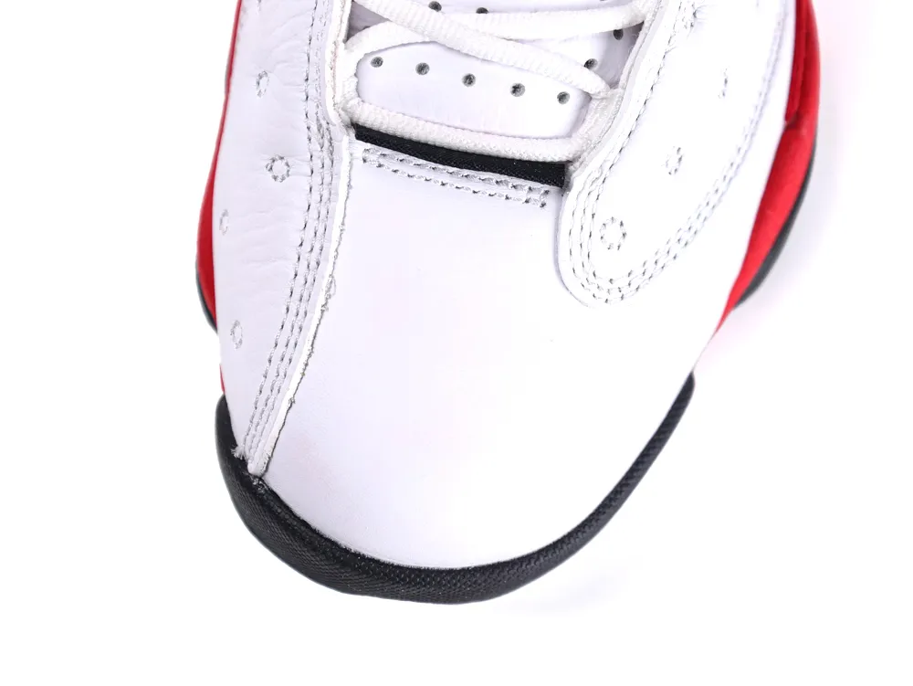 White leather sneaker toe with red and black accents, featuring perforated design.
