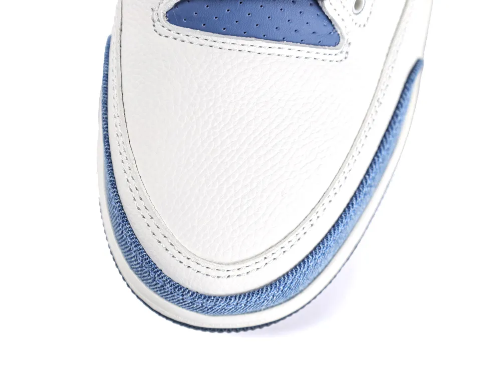 Overhead shot of the white leather toe box bordered by blue denim and a navy blue perforated tongue.