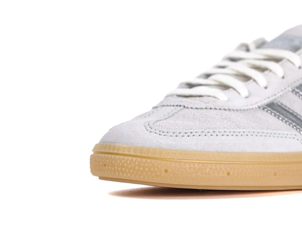 Gray suede sneaker with white laces and beige rubber sole, close-up view.