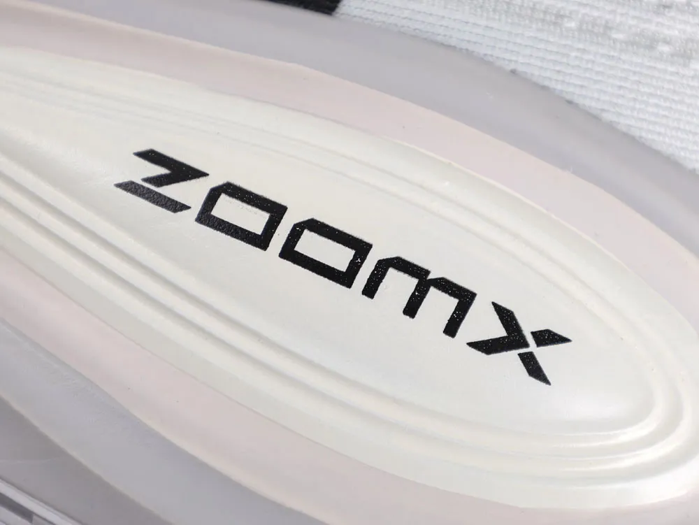 Close-up of beige foam sole with black "ZoomX" text, showcasing material and branding.