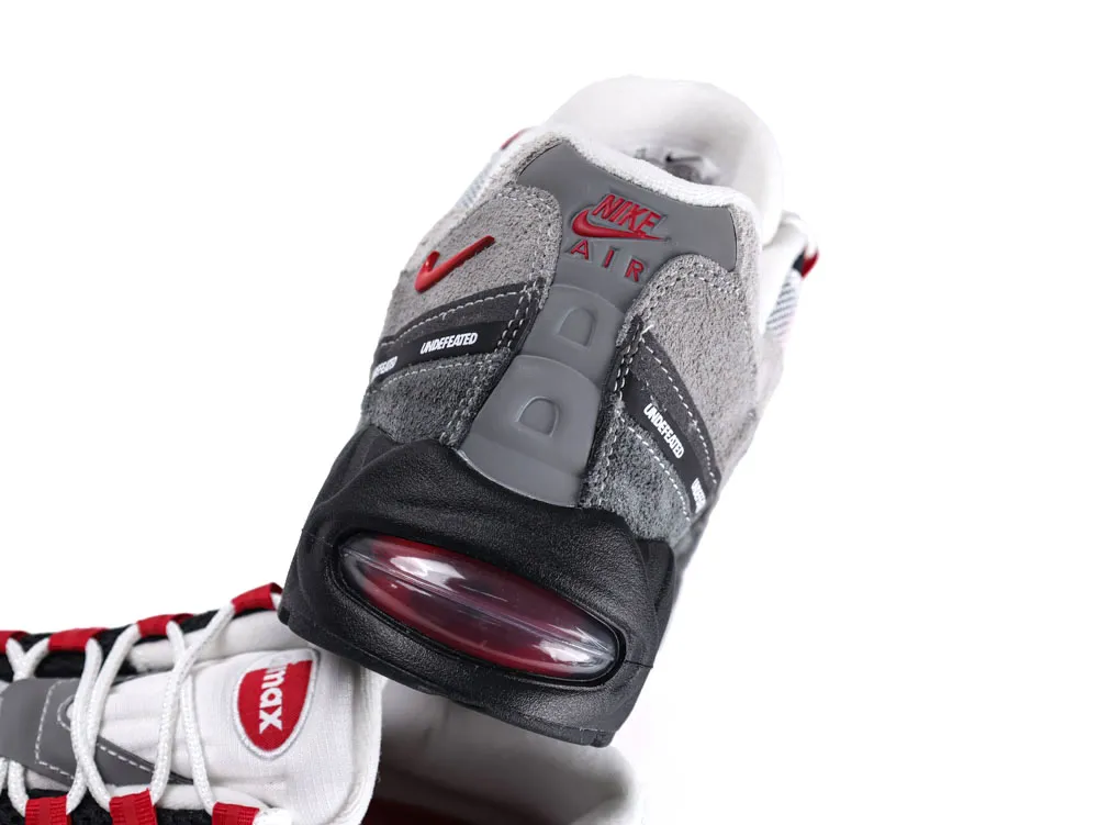 Gray suede and mesh sneaker with black and red accents, featuring visible Air unit.