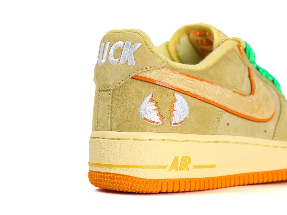 Yellow suede sneaker with orange accents and embroidered details on the heel.
