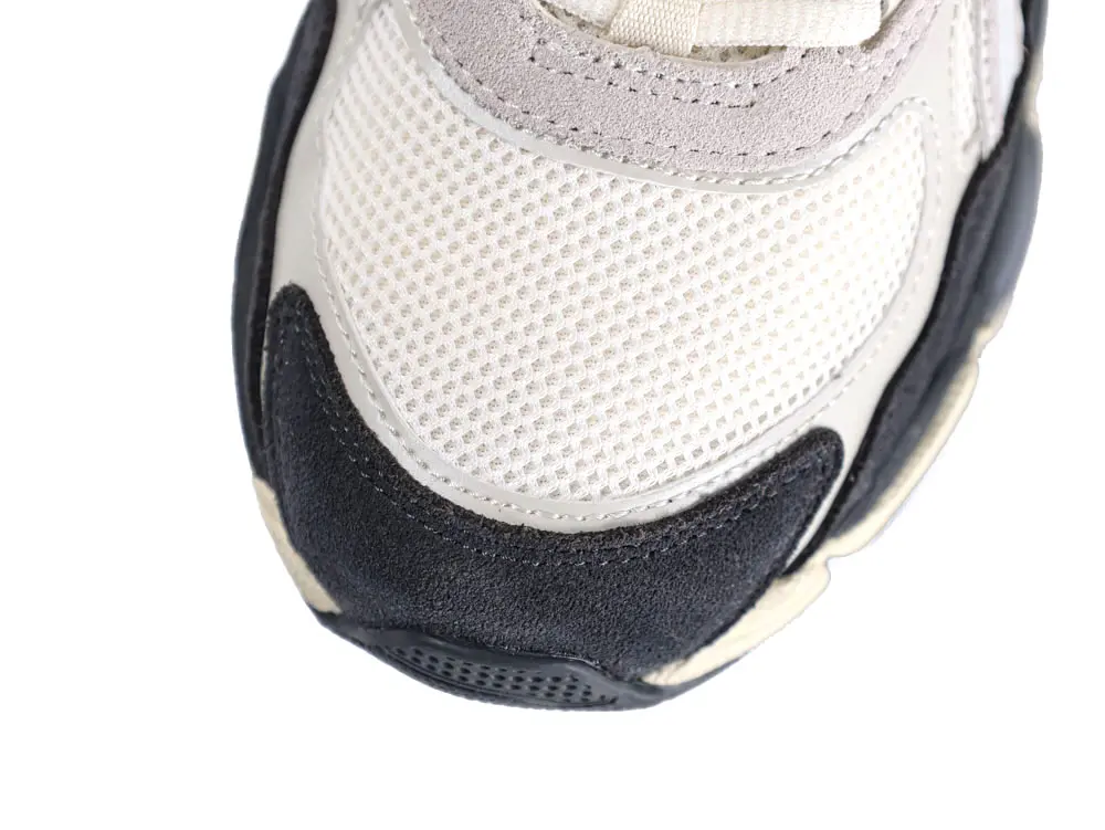 White mesh sneaker toe with black suede overlay, featuring a beige midsole.