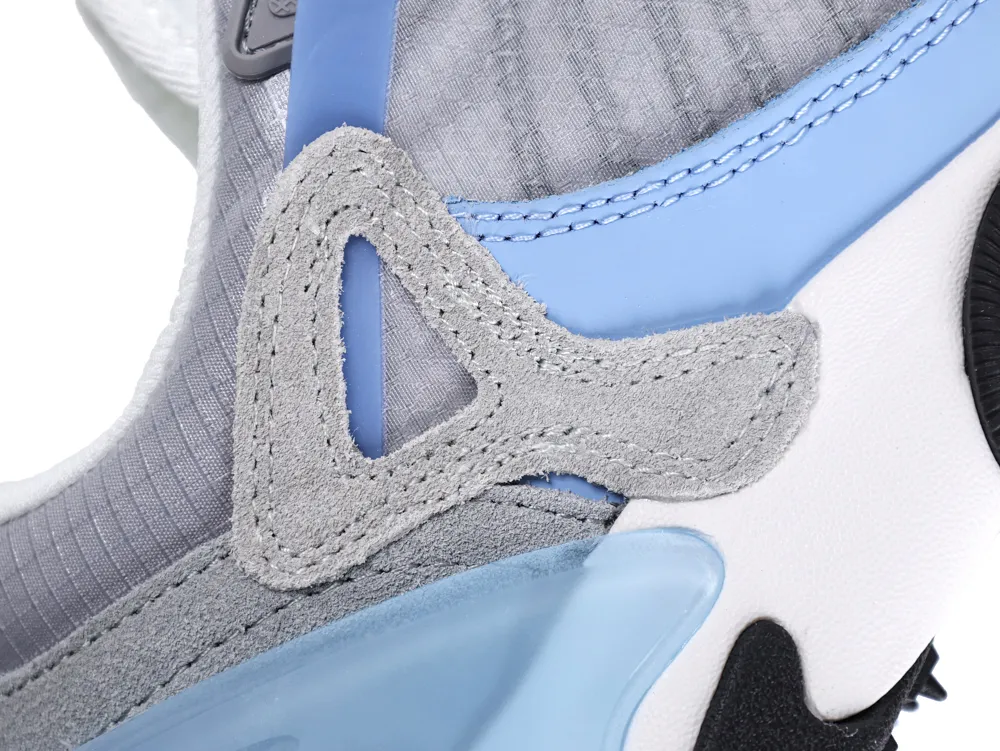 Close-up of a sneaker with blue and gray suede, fabric, and plastic detailing.