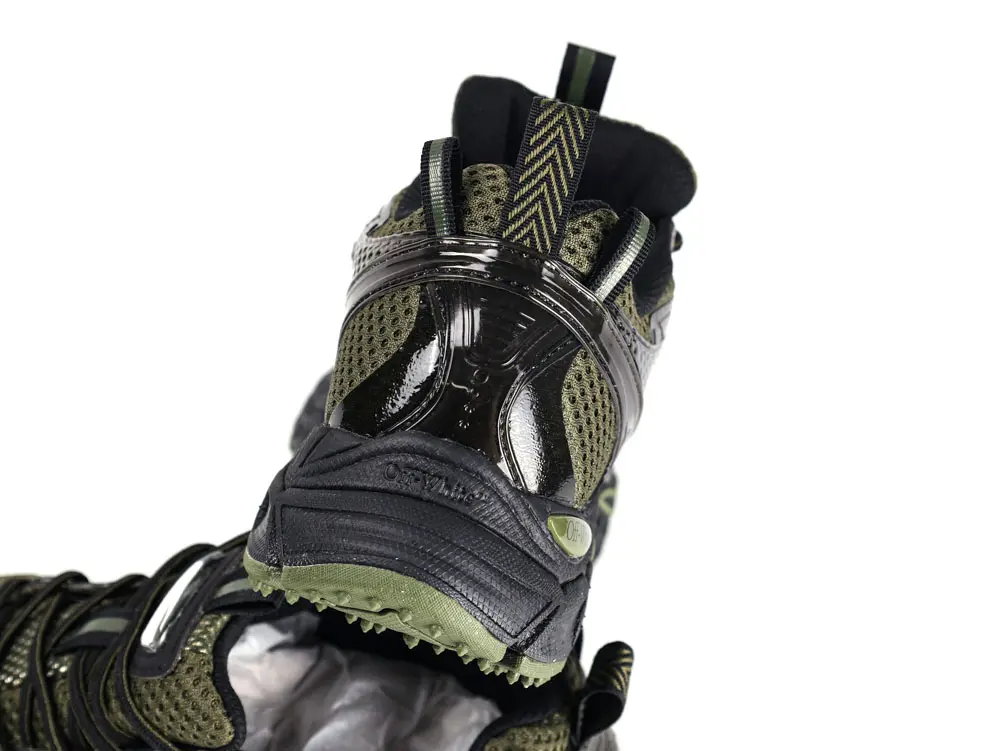 Rear view of black and dark green mesh trainer showing heel counter, pull tab, and textured outsole