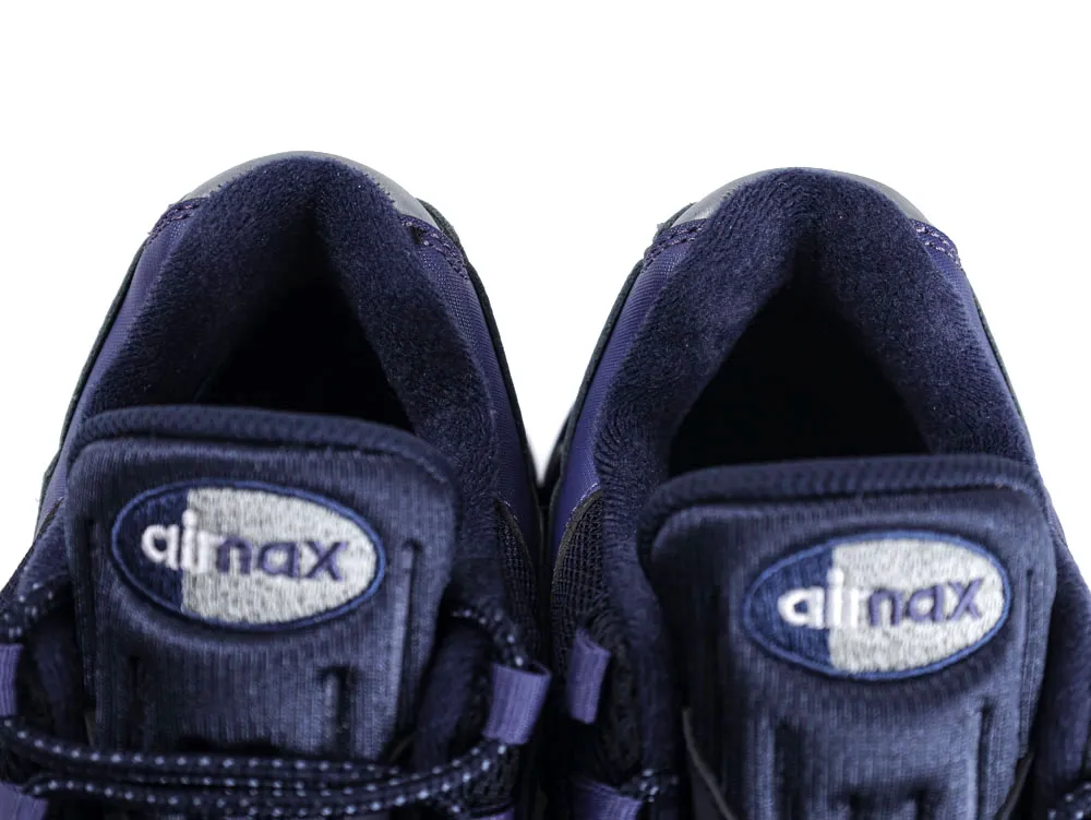 Close-up of a navy blue fabric sneaker tongue with embroidered logo detail.