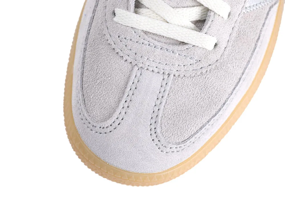 Close-up of a gray suede sneaker with white laces and tan rubber sole.