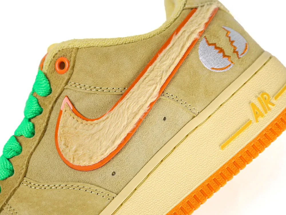 Tan suede sneaker with orange trim, fuzzy swoosh, and green laces.