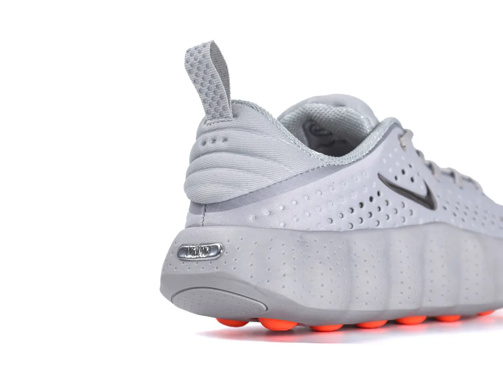 Gray sneaker with mesh fabric, featuring an orange rubber sole and heel tab.