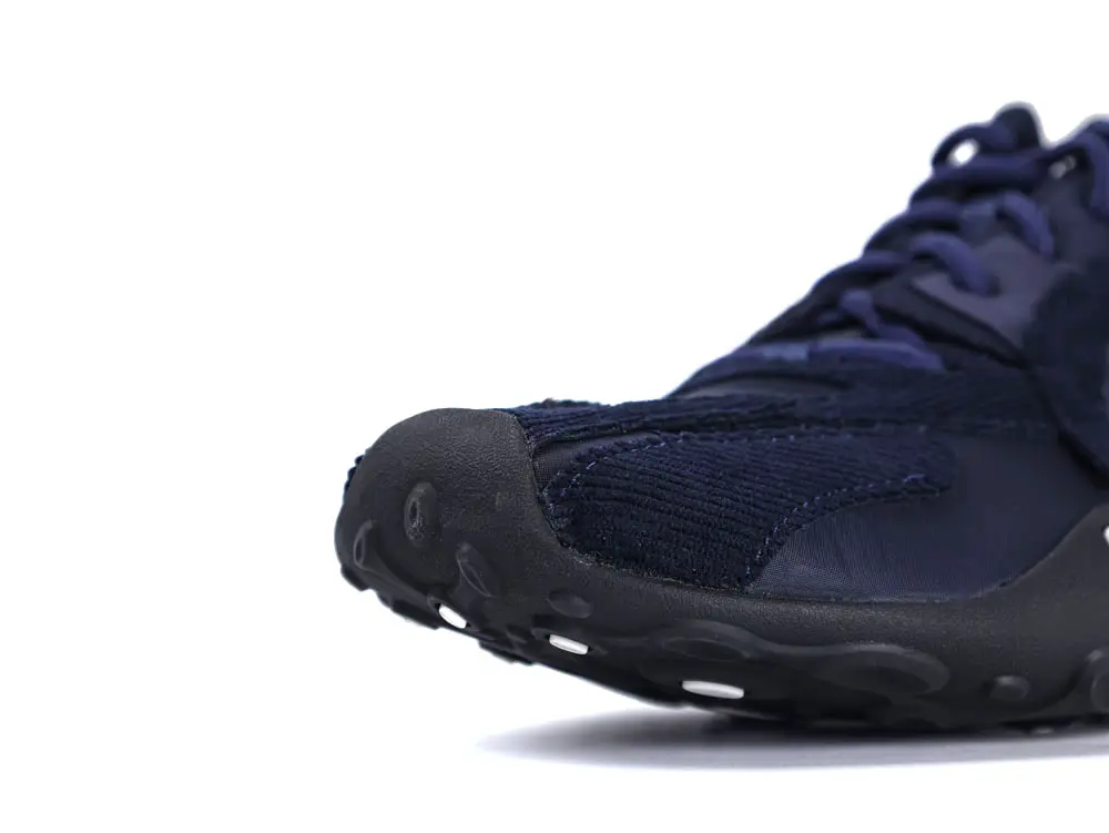 Navy blue sneaker with fabric upper and black rubber sole, close-up view.