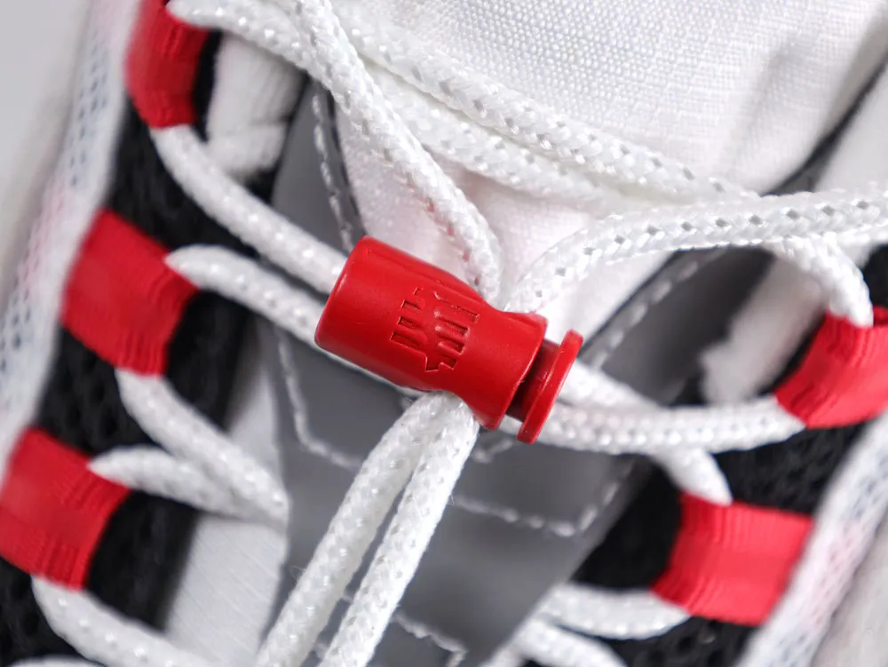 Close-up of red plastic lace lock and white laces on a sneaker.