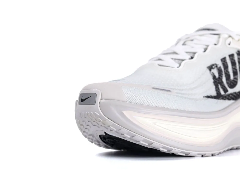 White synthetic running shoe with black accents and textured sole close-up.
