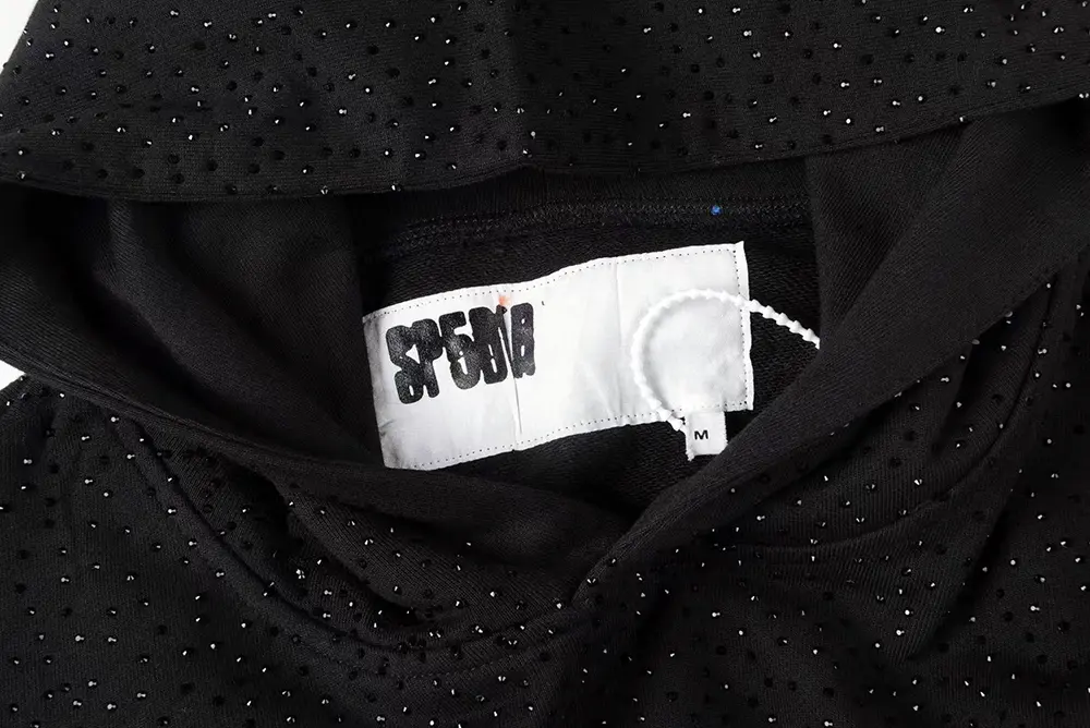 A close-up of the neck tag area of the Sp5der VVS Hoodie in Black, showcasing the material and the cotton lining of the hoodie interior.