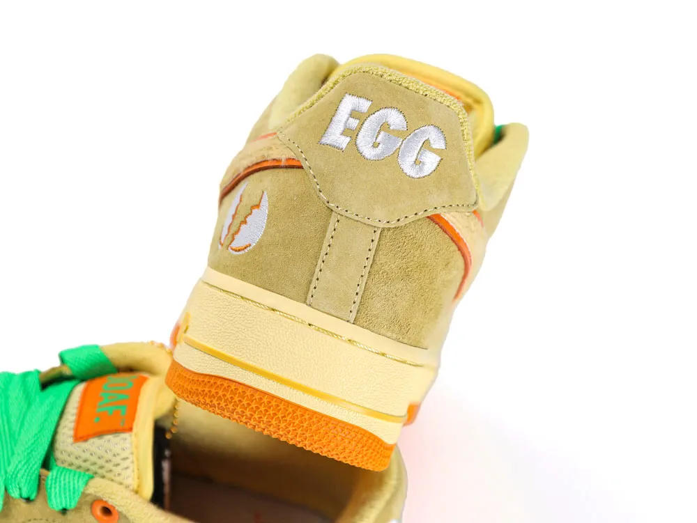 Yellow and orange suede sneaker heel with embroidered details and green laces.