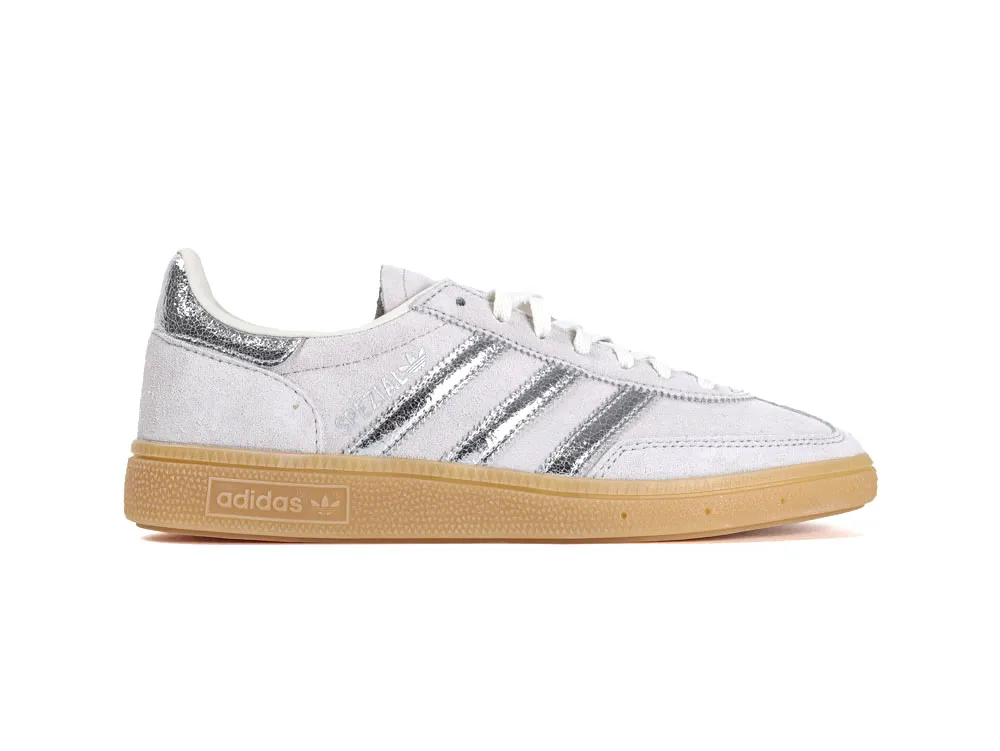 White suede sneakers with silver metallic stripes and a tan rubber sole.