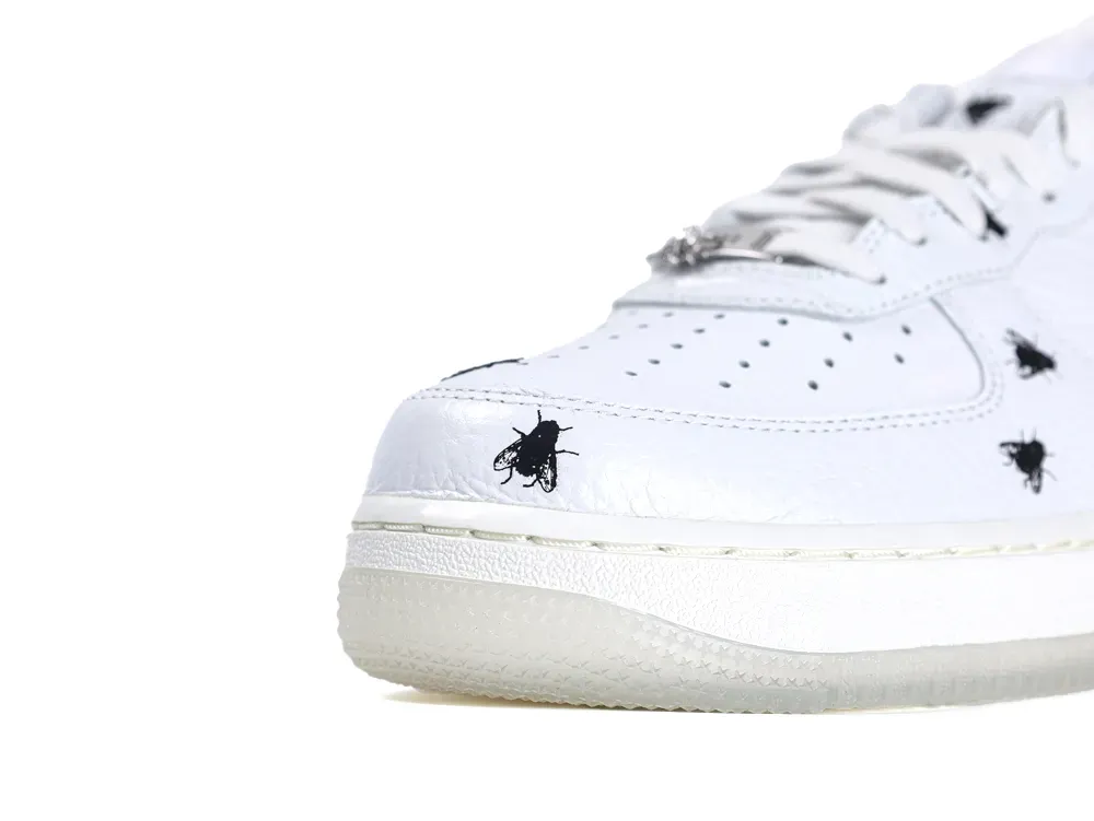 White leather sneaker with black fly print, featuring perforated toe and translucent sole.