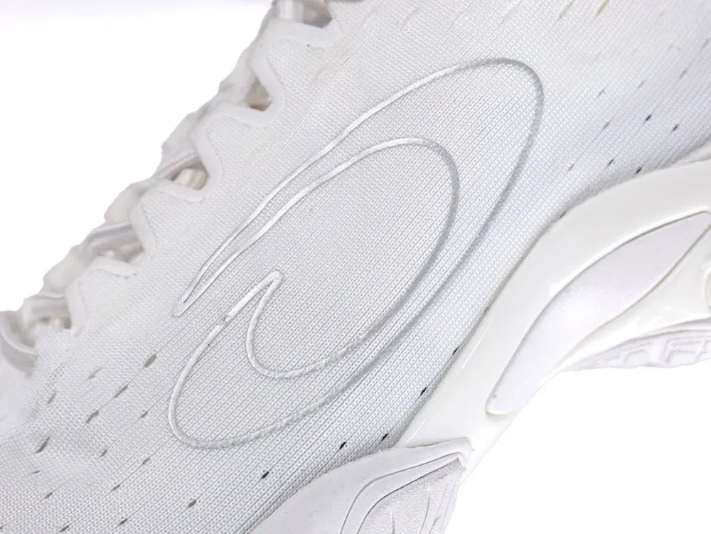 Close-up of a white fabric sneaker upper with embossed logo detailing.