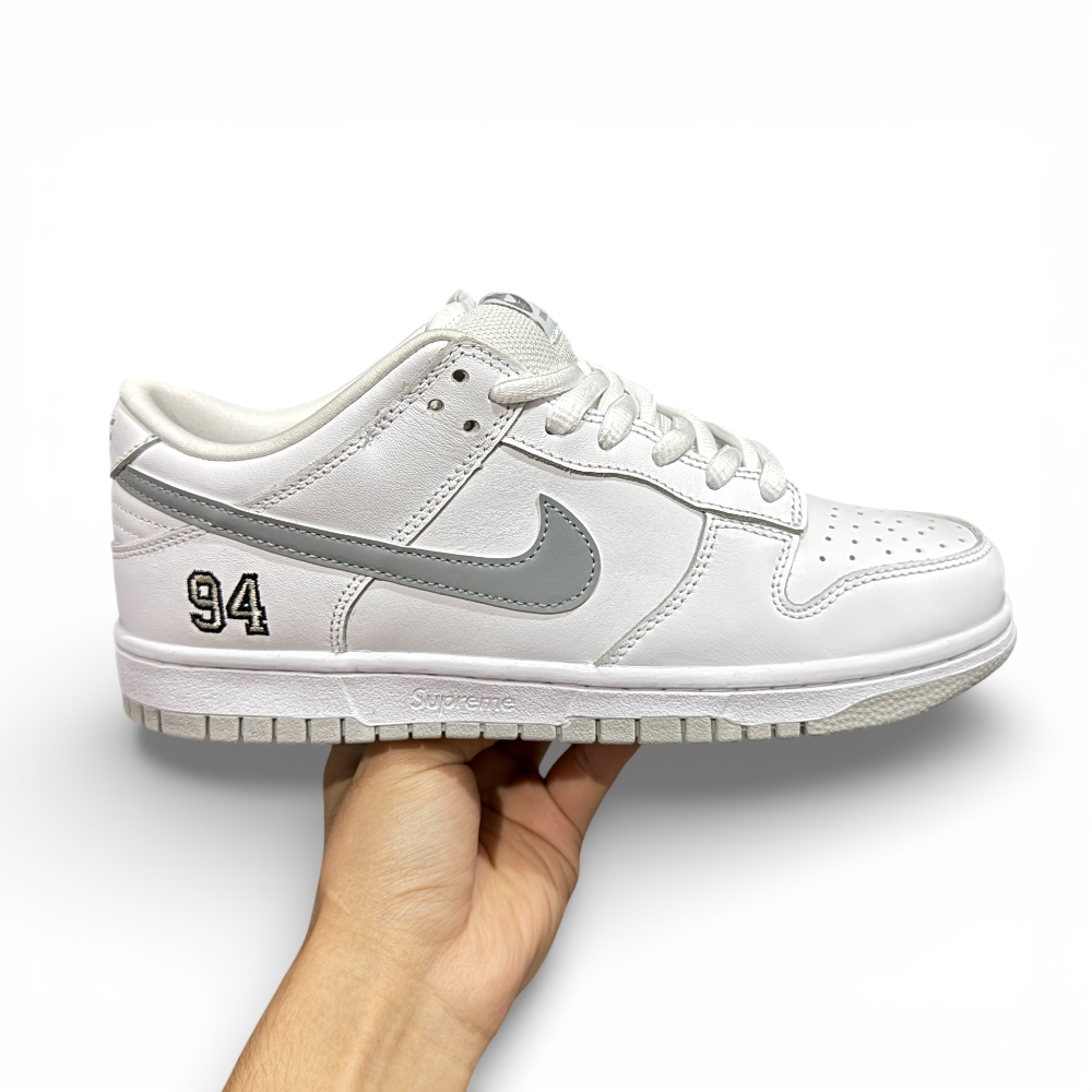 Opposite side view of white low-top sneaker showing embroidered number detail and layered leather panels