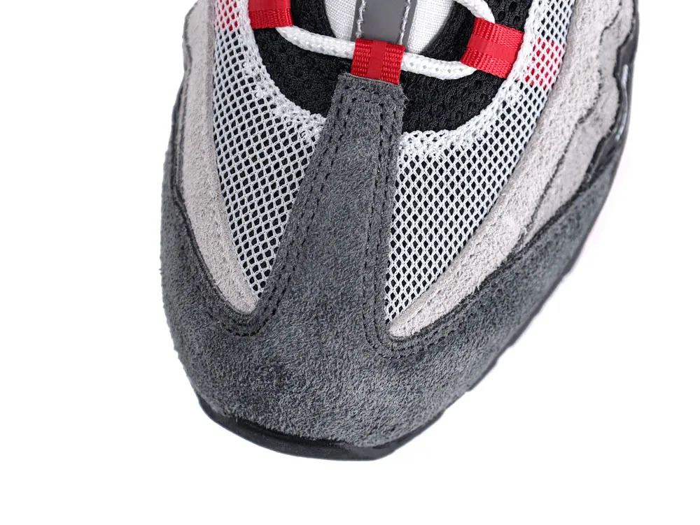 Gray suede sneaker with white mesh and red accents on the toe.