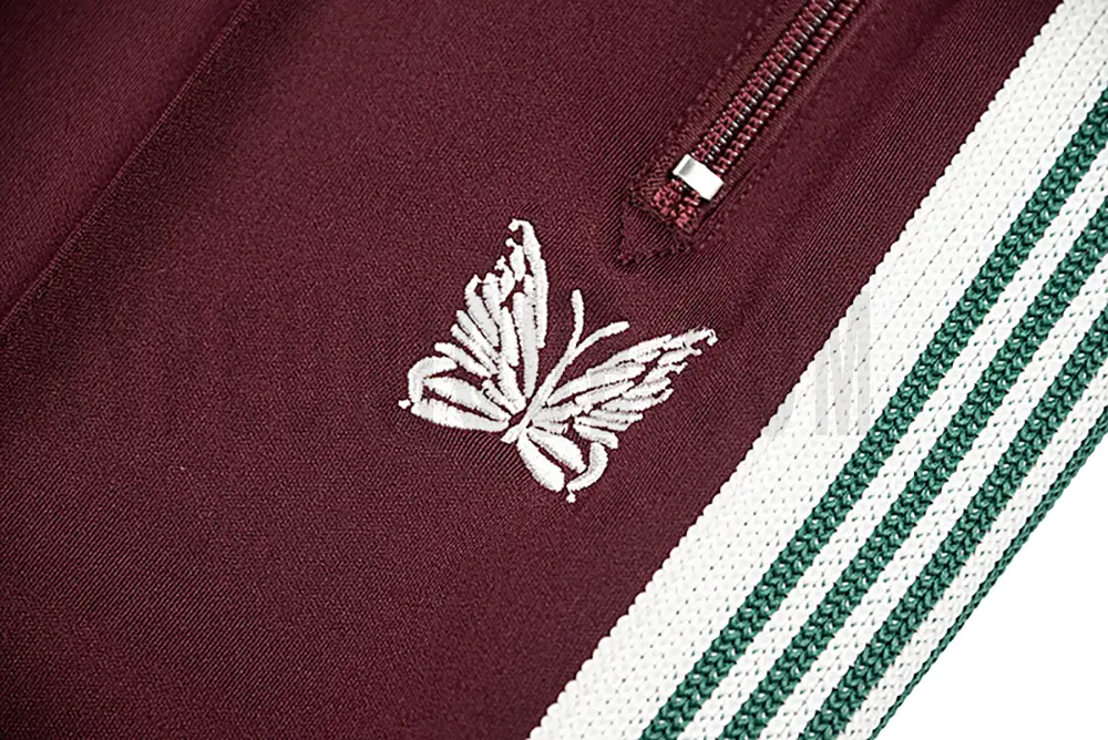 Close-up detail of the track pants pocket and delicate butterfly embroidery.